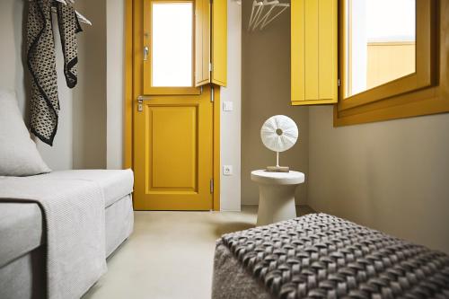 a bedroom with a yellow door and a bed with a fan at Elaia Luxury Suites Mykonos in Mýkonos City
