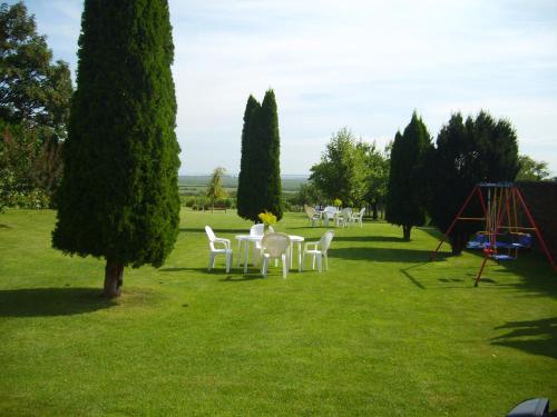 a group of white chairs and a playground in a park at Szűts Vendégház in Fertőrákos