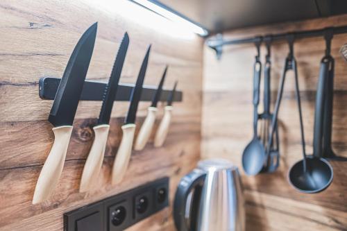 a row of knives hanging on a wooden wall at Apartmány Pod Jelenkou in Orlické Záhoří 