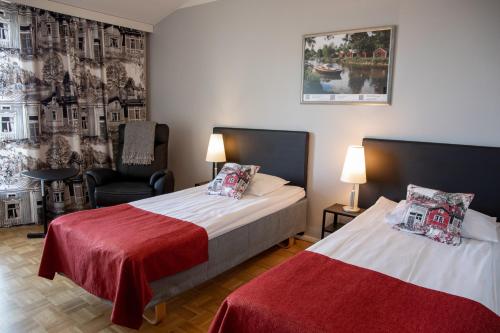 a hotel room with two beds and a chair at Hotel Kokkola in Kokkola