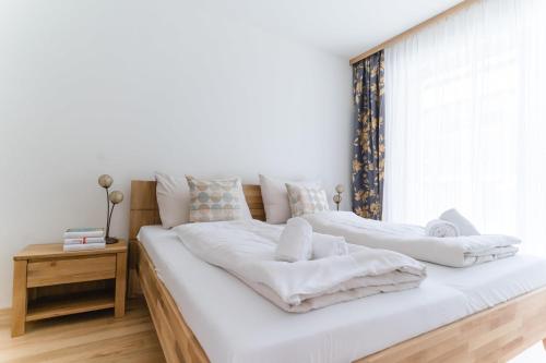2 Betten in einem Schlafzimmer mit weißer Bettwäsche und einem Fenster in der Unterkunft Apartments Oasis Wörthersee neu & zentral in Krumpendorf am Wörthersee