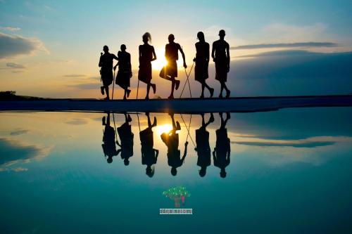 a group of people walking in front of the sunset at Oldarpoi Wageni Camps in Keekorok
