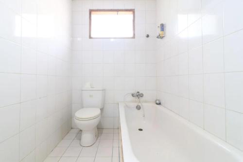 y baño blanco con aseo y bañera. en Urbanview Hotel Mroom PH, en Yakarta