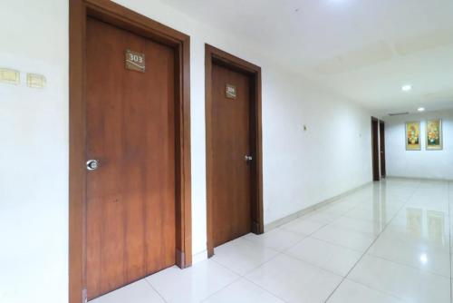 un pasillo con 2 puertas de madera en un edificio en Urbanview Hotel Mroom PH, en Yakarta