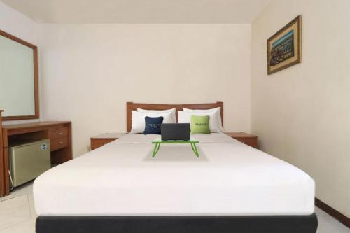 1 dormitorio con 1 cama blanca grande y ordenador portátil. en Urbanview Hotel Mroom PH, en Yakarta