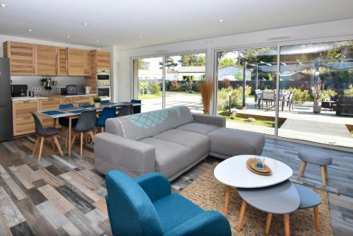 - un salon avec un canapé, des tables et des chaises dans l'établissement Le Lodge, à Saint-Jean-de-Monts