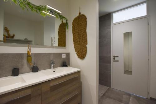 een badkamer met een wastafel en een spiegel bij Le Lodge in Saint-Jean-de-Monts