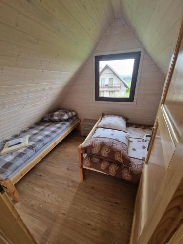 2 łóżka w pokoju na poddaszu z oknem w obiekcie Domki Harnaś Energylandia w mieście Przeciszów