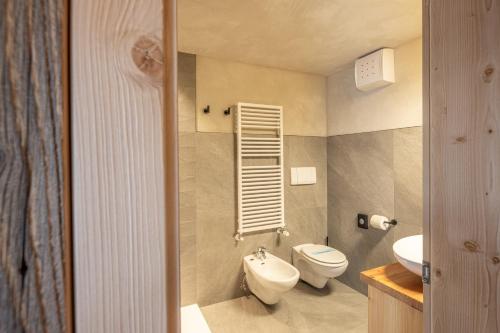 a small bathroom with a toilet and a sink at La Roccia Wellness Hotel in Cavalese