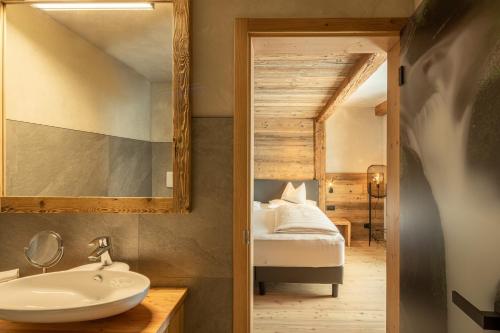 a bathroom with a sink and a bed in a room at La Roccia Wellness Hotel in Cavalese