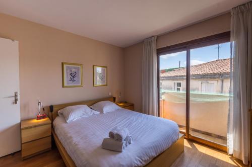 une chambre avec un grand lit et une grande fenêtre dans l'établissement Carré du roi - Première conciergerie, à Montpellier
