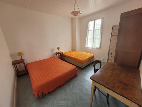 une chambre avec deux lits et une table et une fenêtre dans l'établissement Charmette Grand, à Mimizan