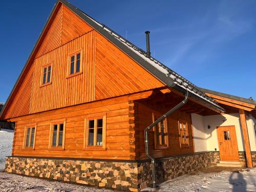 a large wooden house with a gambrel roof at Apartmány Pod Jelenkou in Orlické Záhoří 