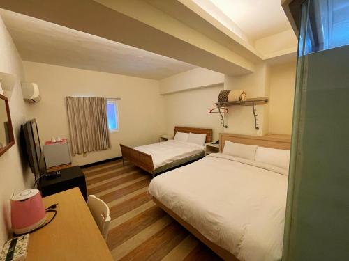 a hotel room with two beds and a desk at Hwa Hong Hotel in Kaohsiung