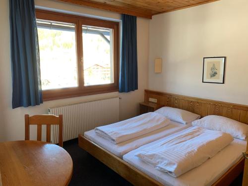 a bedroom with a bed and a table and a window at Mai-Brunn Alm Appartements, Maibrunnenweg 34-36 in Bad Kleinkirchheim