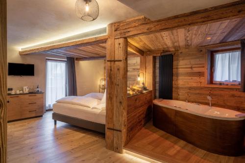 a bedroom with a bed and a bath tub at La Roccia Wellness Hotel in Cavalese