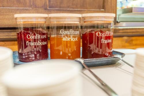 a group of four jars of jam and liquid at Hôtel The Originals City Le Berry - proche centre-ville - Gare in Bourges