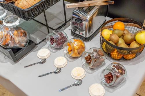 a table with a bunch of bowls of fruit and spoons at Hôtel The Originals City Le Berry - proche centre-ville - Gare in Bourges