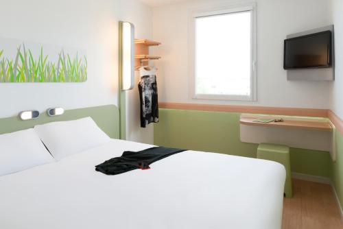 a bedroom with a white bed and a television at Hotel Ibis Budget Lyon Eurexpo - in Chassieu