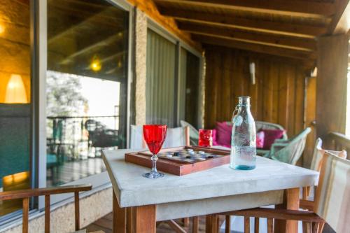 a table with a wine glass and a bottle on a porch at Pedra Bela - Cozy House w/ Private Jacuzzi @ Geres in Terras de Bouro