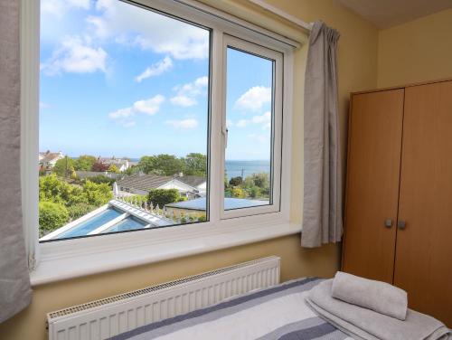 a bedroom with a large window with a view of a pool at Anwylfa in Moelfre