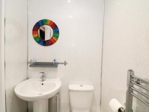 a bathroom with a sink and a toilet and a mirror at Wisteria Cottage in Paignton