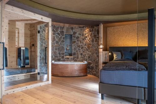 a bedroom with a bed and a tub in a room at La Roccia Wellness Hotel in Cavalese