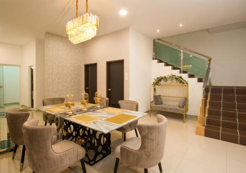 una sala da pranzo con tavolo, sedie e lampadario pendente di L.O.V.E Suite a Batu Pahat