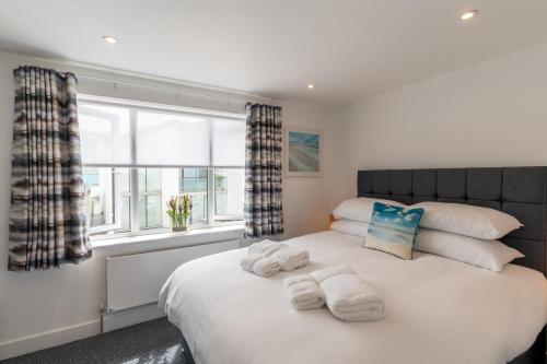 a bedroom with a large white bed with towels on it at No.1 The Prom in Westward Ho