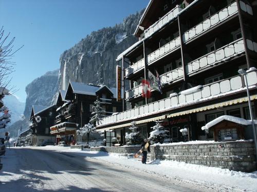 a person standing in the snow in front of a building at Hotel Oberland in Lauterbrunnen