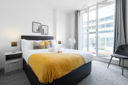 a bedroom with a large bed with a yellow blanket at Exotic 2 Bedroom City Apartment - Free Parking in Birmingham