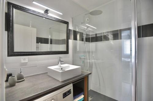 y baño blanco con lavabo y ducha. en Le Cannois, en Le Cannet