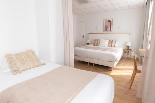 a white bedroom with two beds and a chair at Hôtel Porte Mars Reims Gare Centre Arena in Reims
