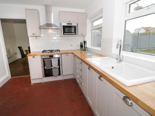 a kitchen with white cabinets and a sink and a window at The Anchorage in Colwyn Bay