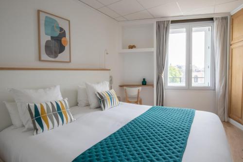 ein Schlafzimmer mit einem großen weißen Bett und einem Fenster in der Unterkunft Hôtel Porte Mars Reims Gare Centre Arena in Reims