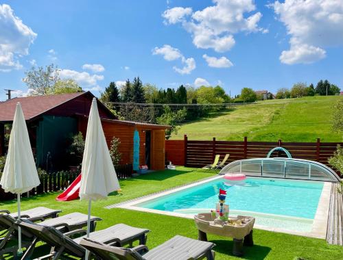 a swimming pool in a yard with chairs and umbrellas at Mese Panzió Zalakaros in Zalakaros