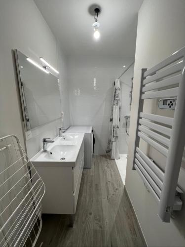 une salle de bain blanche avec un lavabo et un miroir dans l'établissement le Rocher, à La Plaine-sur-Mer