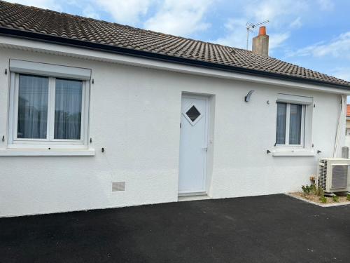 uma casa branca com uma porta branca e janelas em le Rocher em La Plaine-sur-Mer