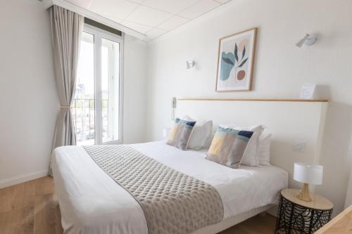 a white bedroom with a bed and a window at Hôtel Porte Mars Reims Gare Centre Arena in Reims