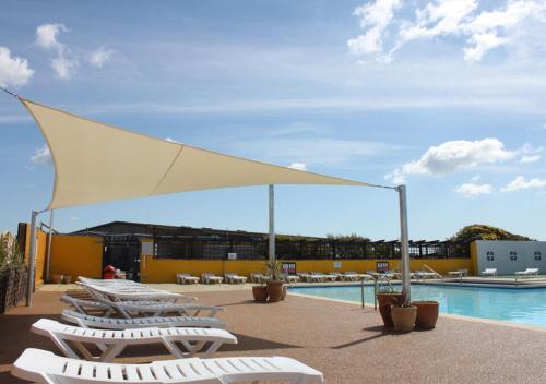 a group of lounge chairs next to a swimming pool at Medmerry Park in Chichester