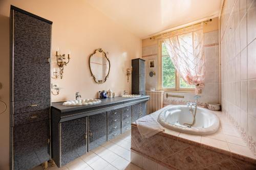 a bathroom with a tub and a sink and a mirror at L'Ile des Iris - à 200 m de la plage in Ver-sur-Mer
