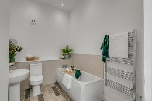 a bathroom with a tub and a toilet and a sink at 4-Bed Countryside Retreat Near Thetford Forest in Snetterton