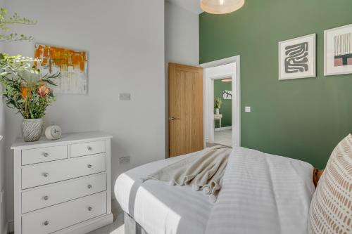 a bedroom with a bed and a white dresser and a mirror at 4-Bed Countryside Retreat Near Thetford Forest in Snetterton