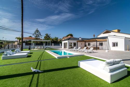 a backyard with a swimming pool and grass at PALM TREE VILLA - 5BDR Paradise Pool / Chill Out Beds in Torremolinos