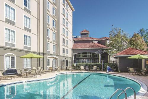 a swimming pool in front of a building with chairs and umbrellas at La Quinta by Wyndham Atlanta Perimeter Medical in Atlanta