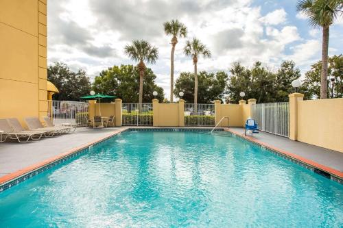 a swimming pool at a resort with palm trees at La Quinta by Wyndham Melbourne Viera in Melbourne