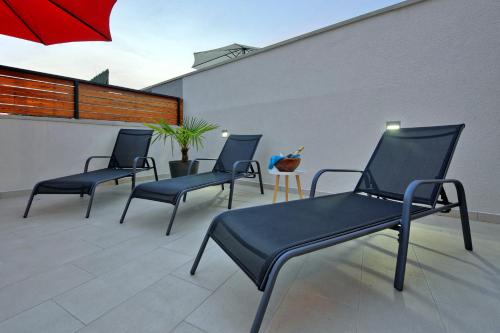 a group of chairs on a patio with a red umbrella at Villa with private pool in village Jadreški in Pula