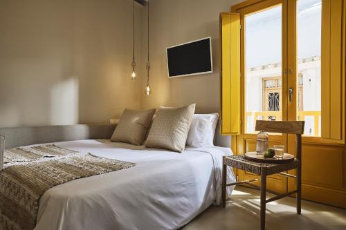 a bedroom with a bed and a window and a table at Elaia Luxury Suites Mykonos in Mýkonos City