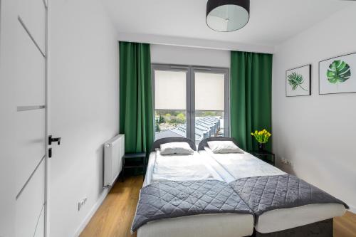 2 łóżka w sypialni z zielonymi zasłonami w obiekcie ALFA 50 we Włocławku