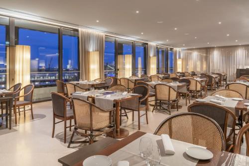 a restaurant with tables and chairs and large windows at Grand Hotel Açores Atlântico in Ponta Delgada